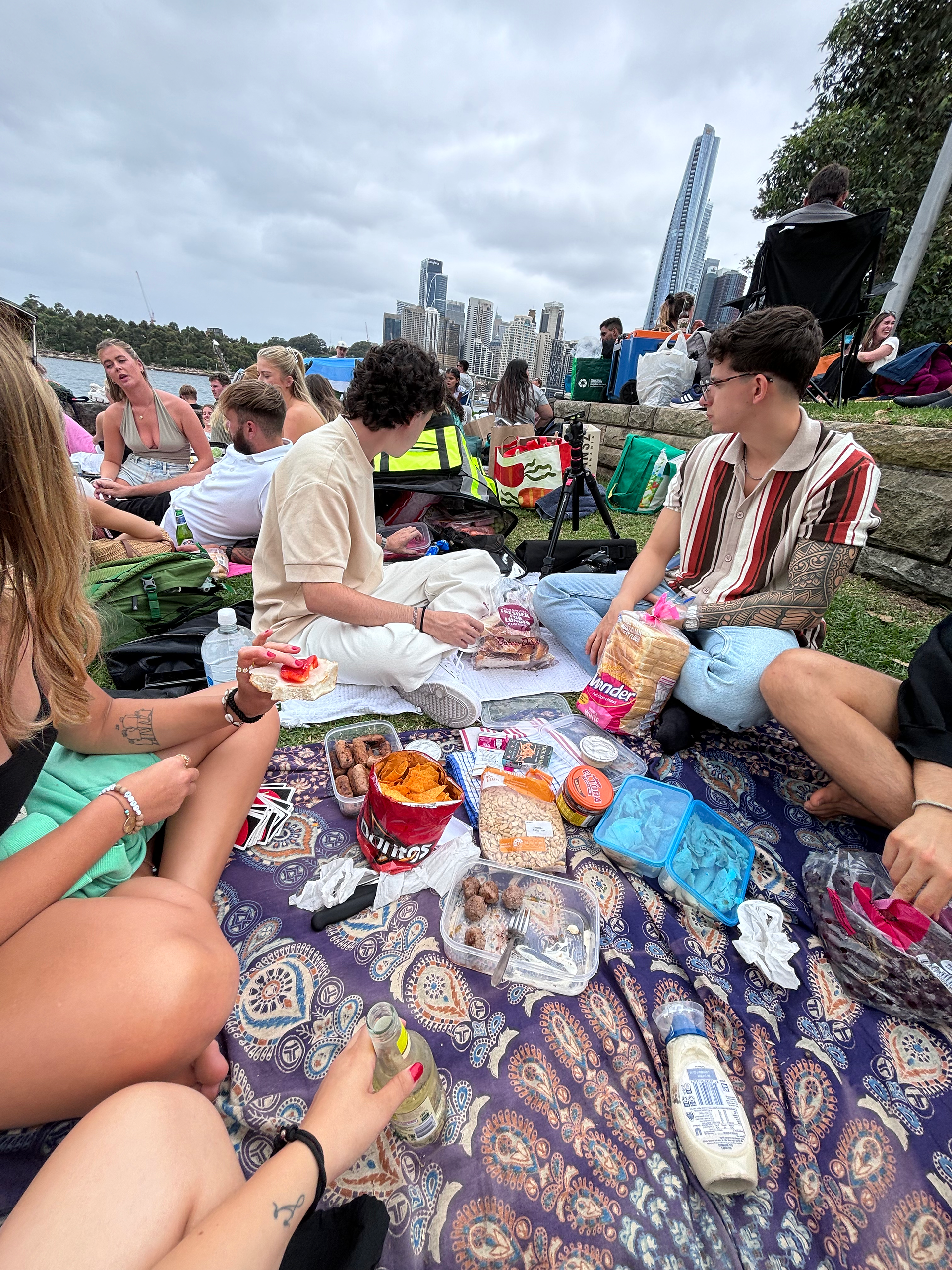 Gente esperando los fuegos artificiales de Año Nuevo en Sydney con mantas y picnic