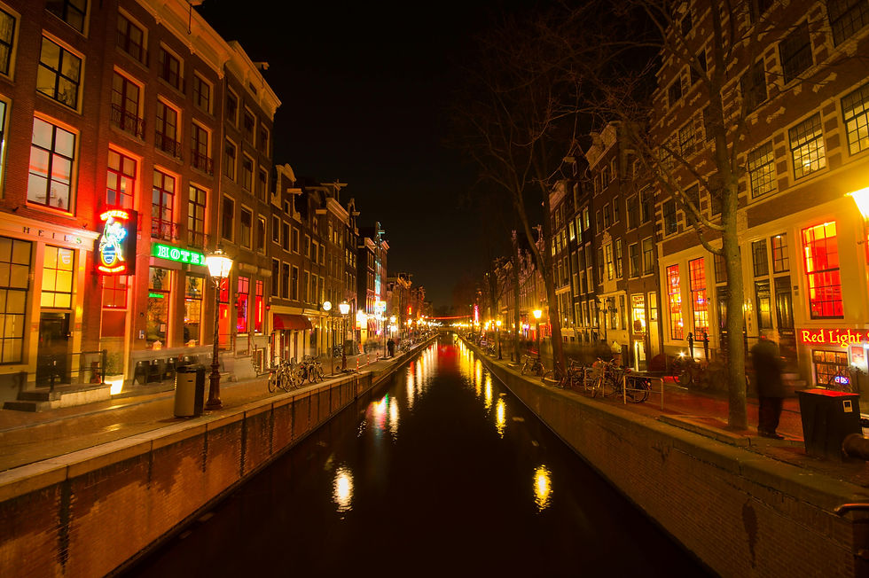 Canal del Barrio Rojo de Ámsterdam de noche con luces rojas y edificios históricos