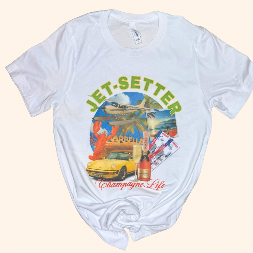 White t-shirt with colorful jetsetter collage design reading “Champagne Life” laid flat on a cream background. Includes a sea