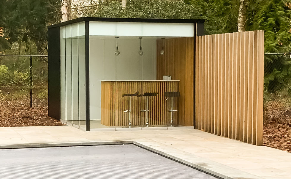 Poolhouse met bar en glaswanden en witte panelen. De vloer is in terrastegels die mee rondom het zwembad liggen. Naast het poolhouse heb je nog een accentmuur in houten balken van thermowood ayous.