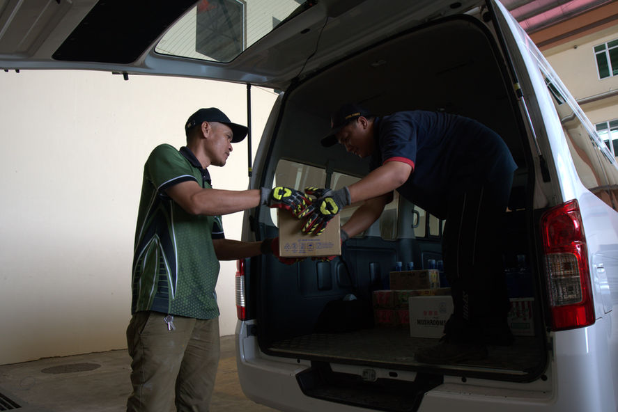 Two men loading boxes to a white van