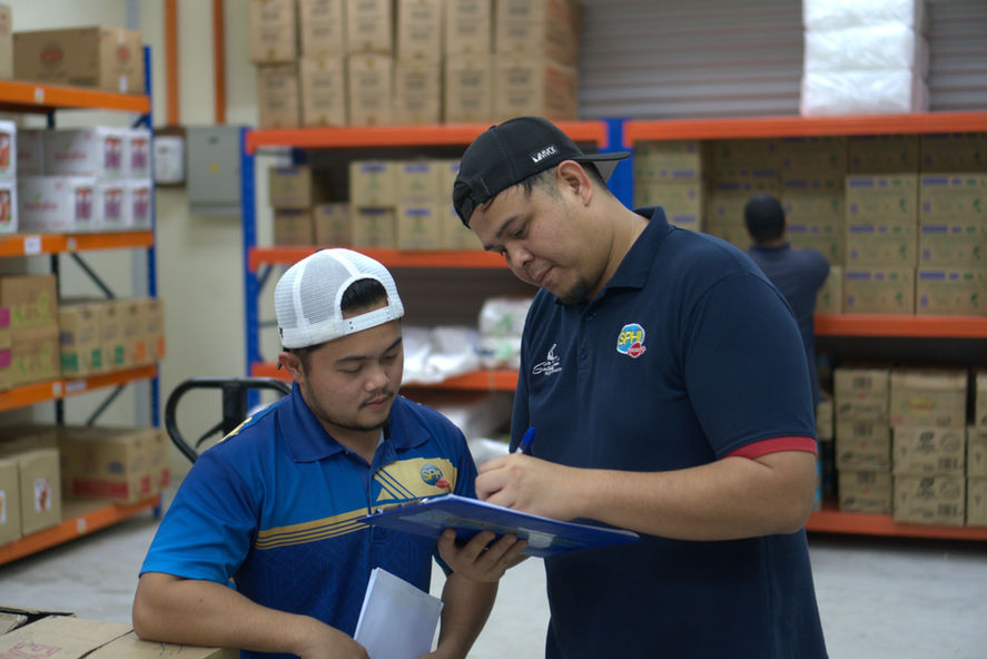 Two men in a warehouse looking at a list on a clipboard