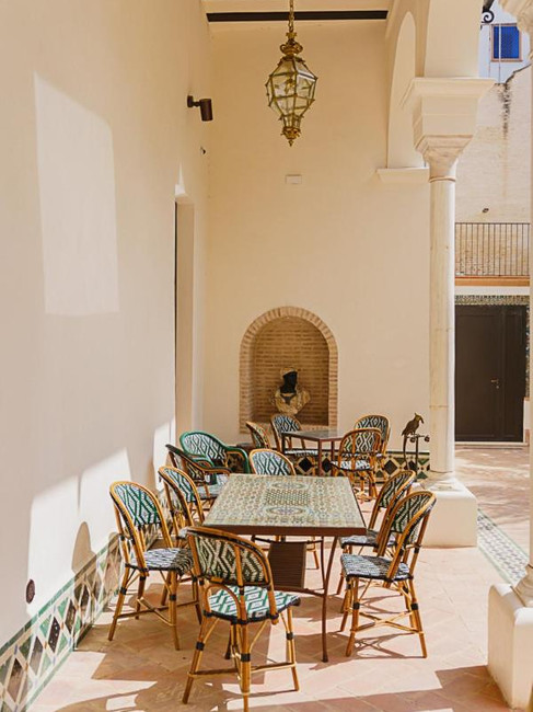 A serene hallway featuring an ornate archway and wrought-iron gate, with patterned flooring and a tapestry on the wall at Hotel Boutique Casa del Limonero, one of my favorite hotels with pool in Seville, Spain