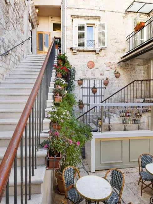 Courtyard of Judita Palace Heritage Hotel in Split, Croatia, showcasing stairs and outdoor tables in front of the building.