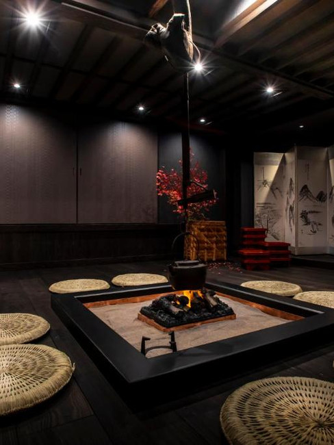 A cozy room at Machiyado Ichiryu featuring a fire pit and a table, ideal for relaxation in Takayama's best ryokan.