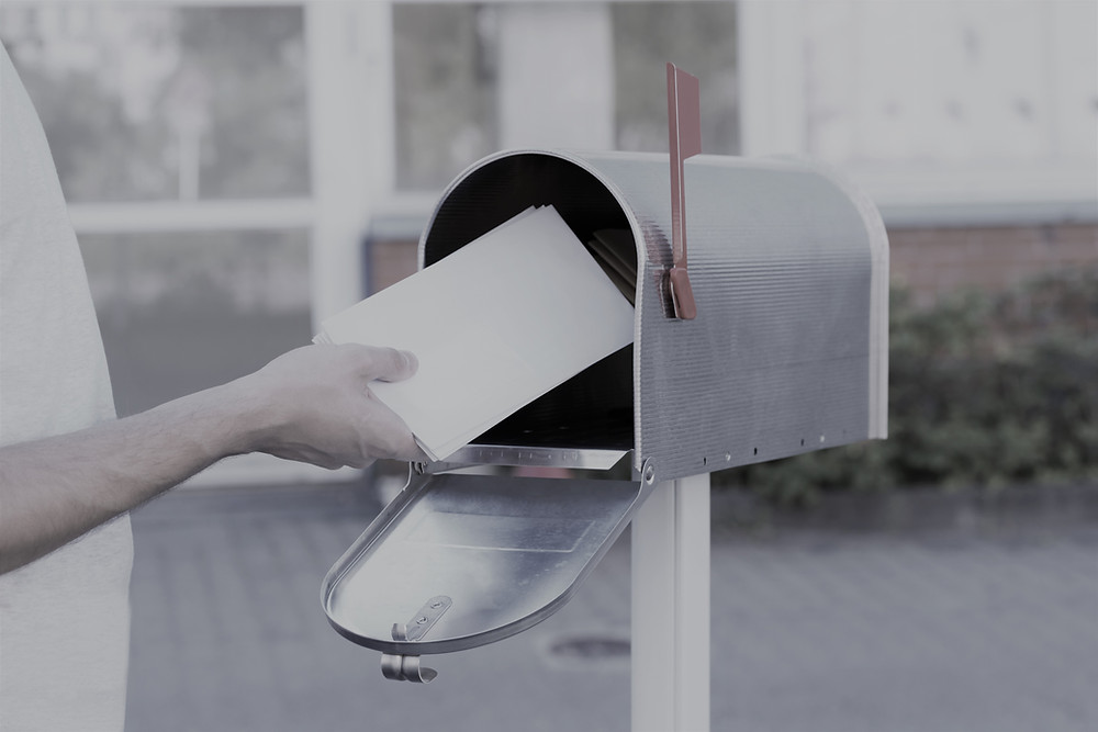 Someone depositing letters in a home mailbox