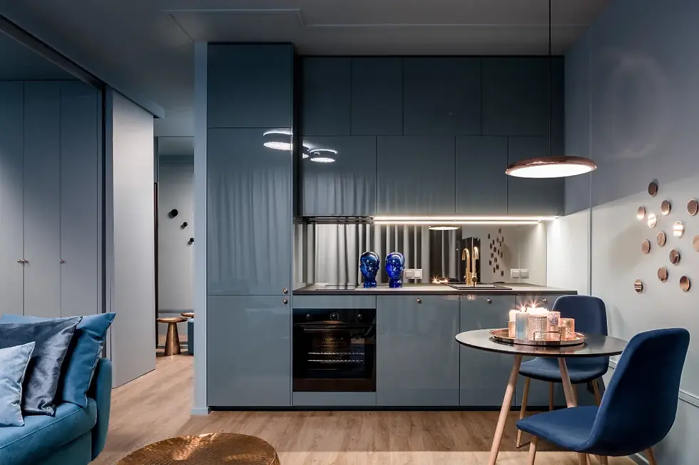 Modern luxury interior design in a compact kitchen and dining area with glossy blue cabinets, wood flooring, ambient lighting, and stylish velvet