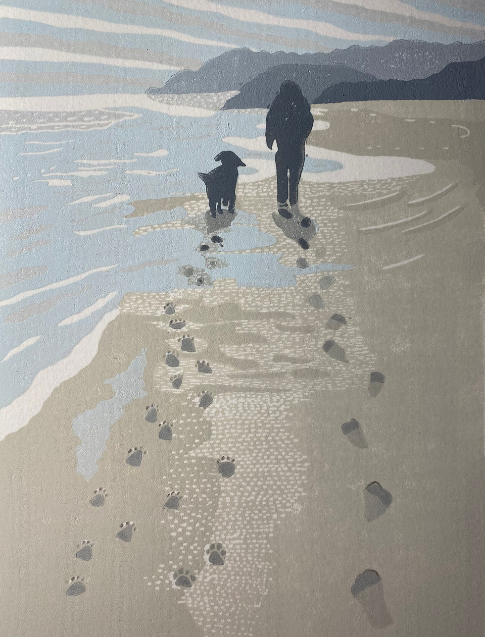 A reduction Lino cut of a man and his dog walking along a beach