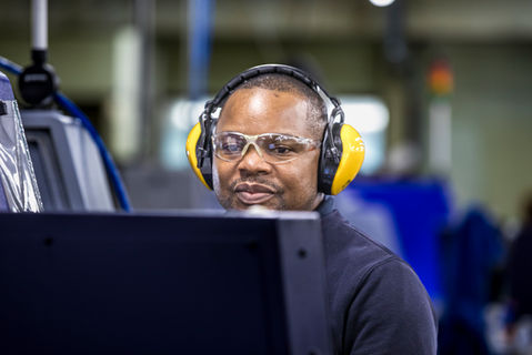 man working in factory with yellow ear defenders