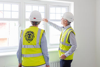 two construction workers looking at windows