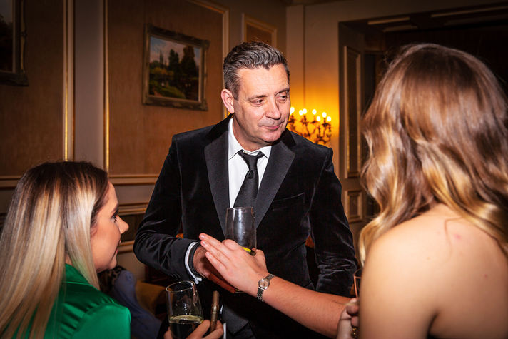 man in black tie and suit discussing at an event