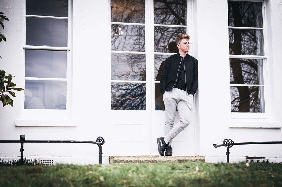 young man leaning against some outside patio doors