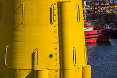 Yellow industrial buoy with water level markings and red boat