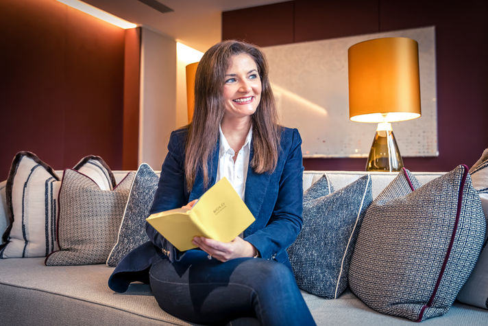 Professional headshot of woman smiling, holding book