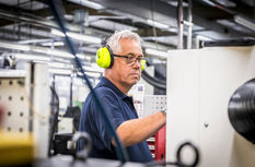 Industrial photographer Sheffield capturing factory worker with yellow ear defenders operating machinery