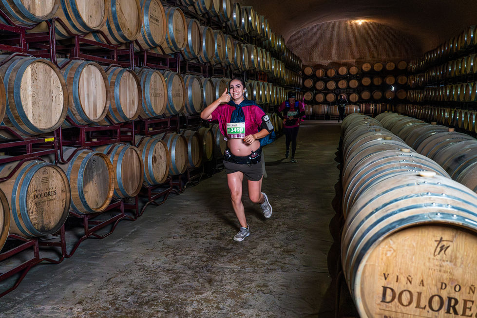 Corredora en bodega entre barriles, Xtrail Viñedos 2025, maratón y carrera de vino.
