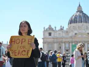 Yona Tukuser holds a "HOPE FOR PEACE" sign in St. Peter's Square at the Vatican during the Conclave