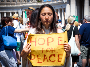 Yona Tukuser holds a "HOPE FOR PEACE" sign in St. Peter's Square at the Vatican during the Conclave