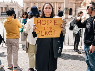 Yona Tukuser holds a "HOPE FOR PEACE" sign in St. Peter's Square at the Vatican during the Conclave