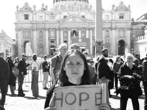 Yona Tukuser holds a "HOPE FOR PEACE" sign in St. Peter's Square at the Vatican during the Conclave