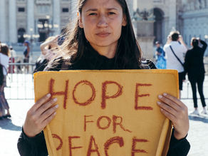 Yona Tukuser holds a "HOPE FOR PEACE" sign in St. Peter's Square at the Vatican during the Conclave
