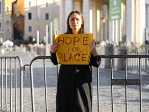 Yona Tukuser holds a "HOPE FOR PEACE" sign in St. Peter's Square at the Vatican during the Conclave