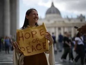 Yona Tukuser holds a "HOPE FOR PEACE" sign in St. Peter's Square at the Vatican during the Conclave