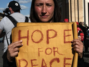 Yona Tukuser holds a "HOPE FOR PEACE" sign in St. Peter's Square at the Vatican during the Conclave