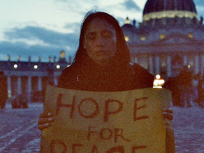 Yona Tukuser holds a "HOPE FOR PEACE" sign in St. Peter's Square at the Vatican during the Conclave