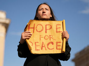 Yona Tukuser holds a "HOPE FOR PEACE" sign in St. Peter's Square at the Vatican during the Conclave