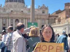 Yona Tukuser holds a "HOPE FOR PEACE" sign in St. Peter's Square at the Vatican during the Conclave