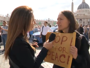 Yona Tukuser holds a "HOPE FOR PEACE" sign in St. Peter's Square at the Vatican during the Conclave