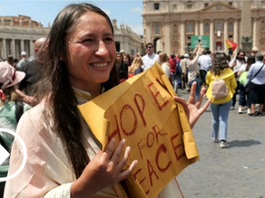 Yona Tukuser holds a "HOPE FOR PEACE" sign in St. Peter's Square at the Vatican during the Conclave
