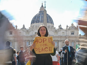 Yona Tukuser holds a "HOPE FOR PEACE" sign in St. Peter's Square at the Vatican during the Conclave