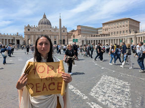 Yona Tukuser holds a "HOPE FOR PEACE" sign in St. Peter's Square at the Vatican during the Conclave