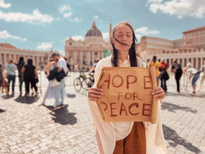 Yona Tukuser holds a "HOPE FOR PEACE" sign in St. Peter's Square at the Vatican during the Conclave
