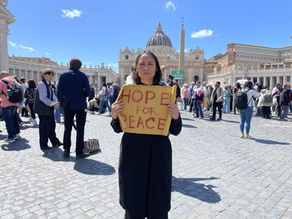 Yona Tukuser holds a "HOPE FOR PEACE" sign in St. Peter's Square at the Vatican during the Conclave