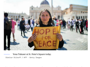Yona Tukuser holds a "HOPE FOR PEACE" sign in St. Peter's Square at the Vatican during the Conclave