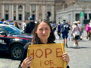 Yona Tukuser holds a "HOPE FOR PEACE" sign in St. Peter's Square at the Vatican during the Conclave
