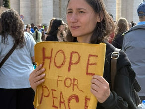 Yona Tukuser holds a "HOPE FOR PEACE" sign in St. Peter's Square at the Vatican during the Conclave