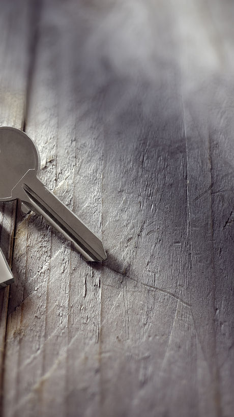 House key on a house shaped keychain resting on wooden floorboards concept for real estate, moving h