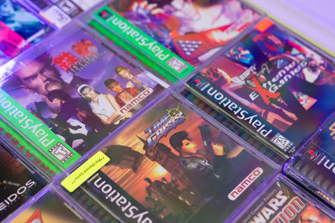 A collection of vintage PlayStation 1 game cases including Tekken and Soul Blade under purple light. Credit goes to "Moments By Migs".