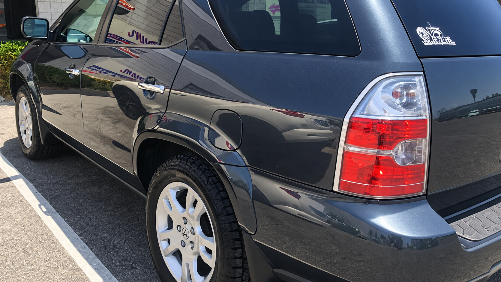 Repaired metallic gray Acura SUV viewed from the rear passenger side, showing its finished quarter panel, door, and wheel arch.