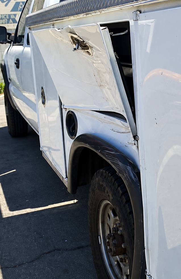 Collision damage on a white utility truck service body