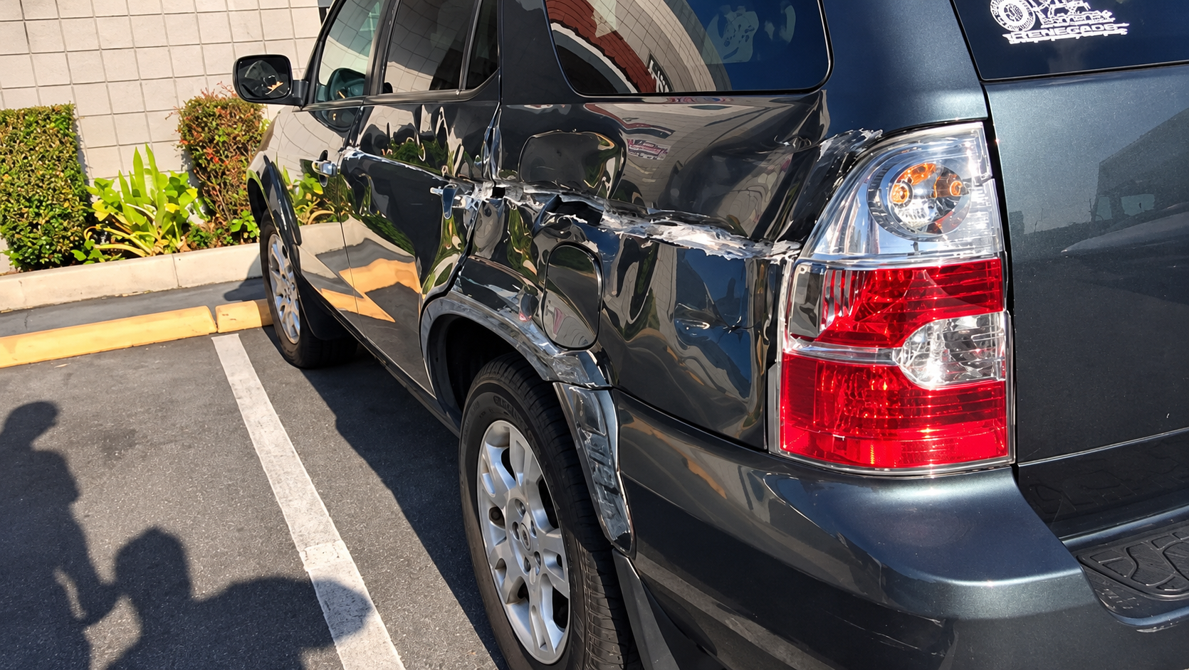 Acura SUV with heavy collision damage along the rear passenger-side door and quarter panel near the taillight.