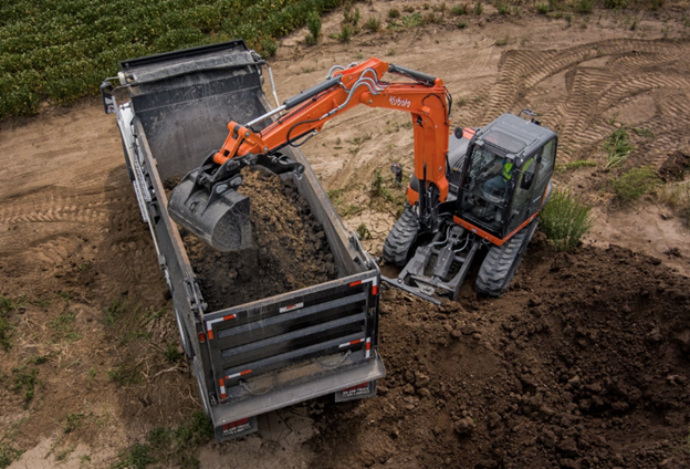 Kubota KX080-5 compact excavator loading dirt into a dump truck at a Southern California job site
