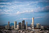 Southern California city skyline at dusk with modern high-rise office buildings and commercial towers under a cloudy blue sky, representing the regional business communities served by SCTS.
