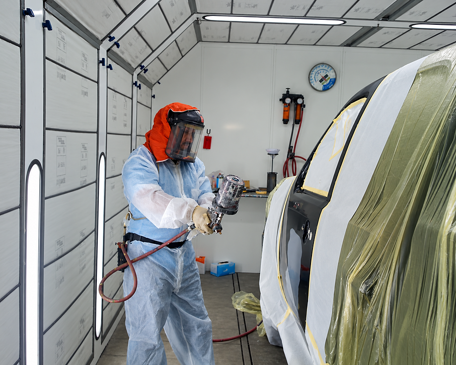 1. Technician performing precision paint work inside an automotive spray booth