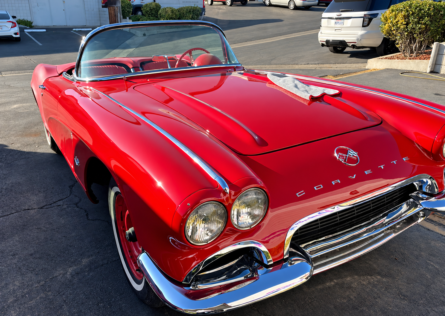 Classic red Chevrolet Corvette convertible photographed from the front, showing chrome bumper, grille, and dual headlights.