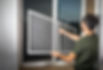 Technician installing a white-framed window screen into a residential window